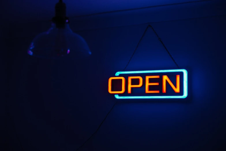 a neon sign that says open hanging on a wall, a stock photo, by Jesper Knudsen, happening, with blue light inside, 6 : 3 0 am, taken with my nikon d 3, convenience store