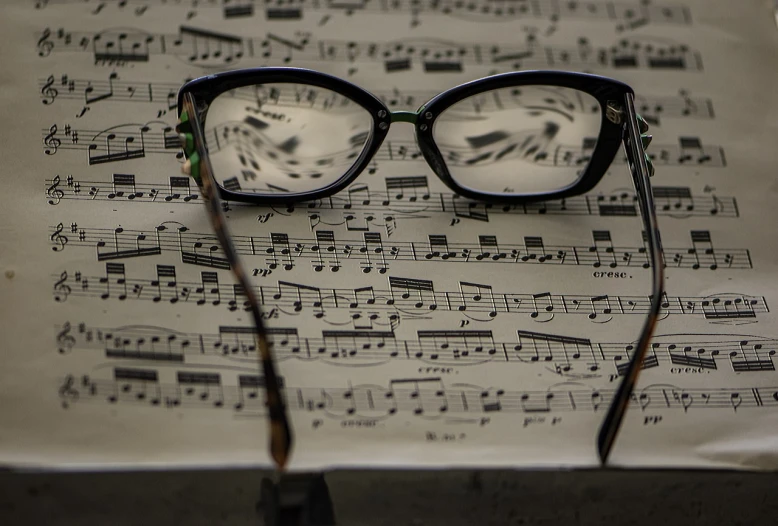 a pair of glasses sitting on top of a sheet of music, a picture, precisionism, many reflections, bass music, blog-photo, music notes