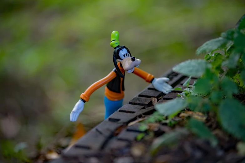 a close up of a toy figure on a train track, inspired by Luigi Kasimir, figuration libre, goofy cartoon, in forest jungle, outdoor photo, daffy duck