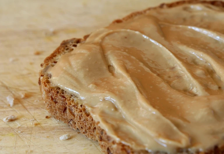 a piece of bread with peanut butter on it, a picture, by Edward Corbett, pexels, close up high detailed, stock photo, recipe, glazed