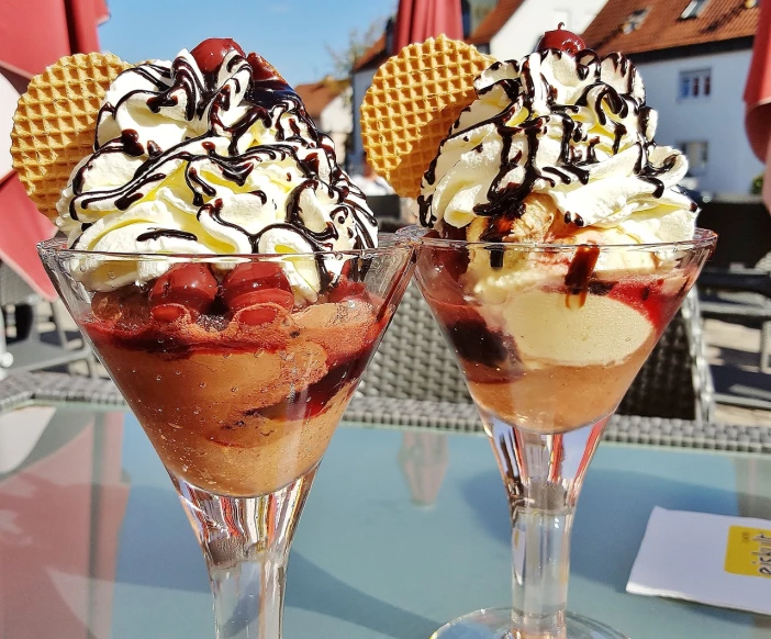 a couple of desserts sitting on top of a table, pixabay, ice cream, red black white golden colors, schnapps, slightly sunny weather