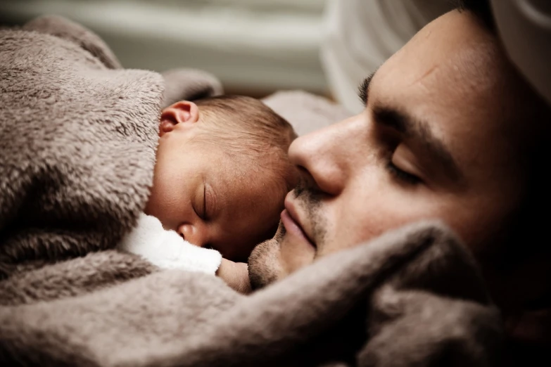 a man holding a baby wrapped in a blanket, laying in bed, highly polished, fast paced, father with child