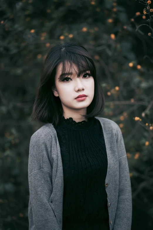 a woman standing in front of a tree, by Jason Chan, unsplash, realism, short black hair with bangs, wearing a dark sweater, popular korean makeup, 19-year-old girl