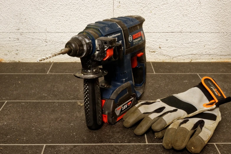 a drill and a pair of gloves on a tiled floor, by Jens Søndergaard, battery, bosch, thicc build, frontshot