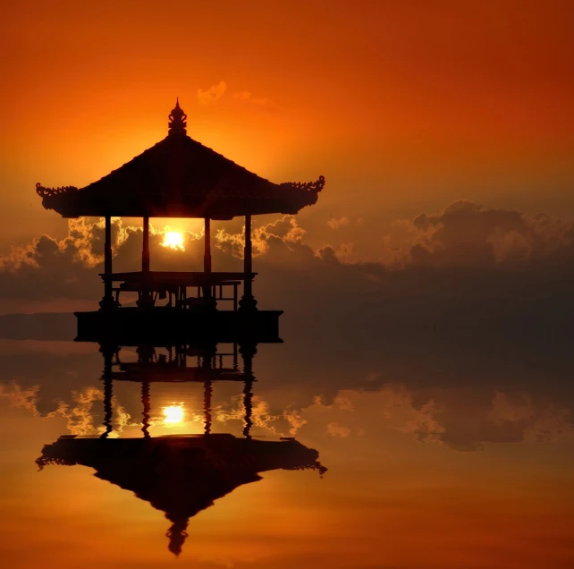 a gazebo sitting on top of a body of water, a picture, by Bernardino Mei, shutterstock, sumatraism, orange glow, stock photo, asian sun, fire reflection