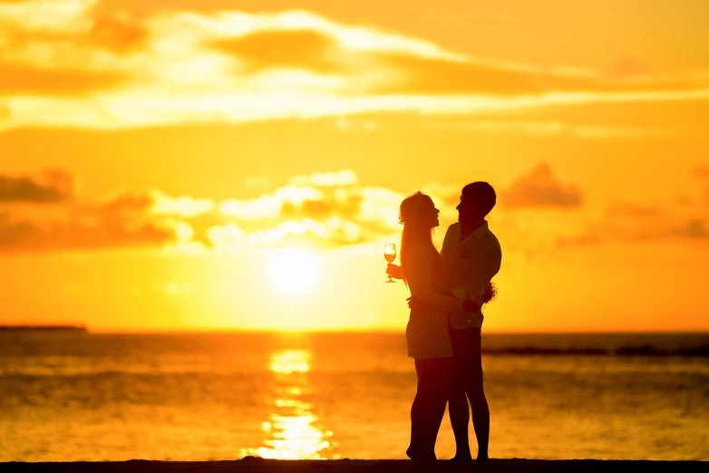 a man and a woman standing on a beach at sunset, shutterstock, romantic!!!, wine, hugs, golden hour photo