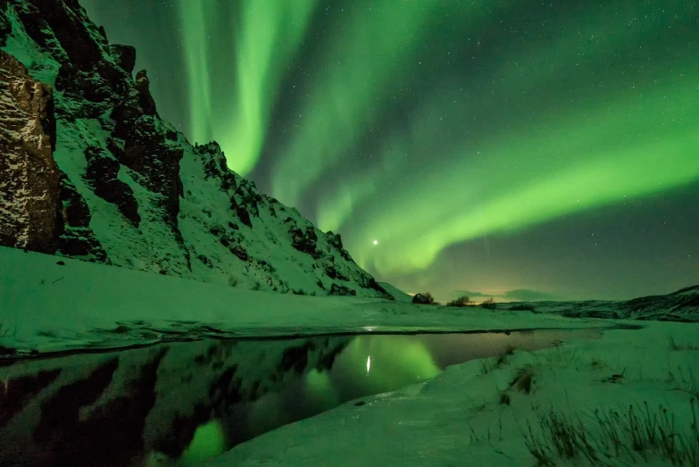 a mountain covered in snow next to a body of water, by Þórarinn B. Þorláksson, pexels contest winner, romanticism, green lights, photographer art wolfe, huge glistening muscles, chris moore”