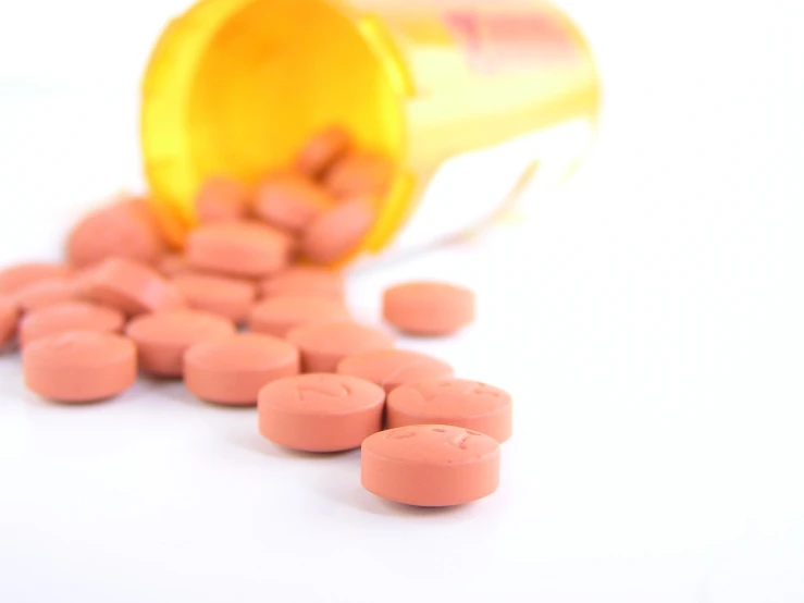 orange pills spilling out of a bottle on a white surface, antipodeans, istockphoto, 3 4 5 3 1, blush, seen from below