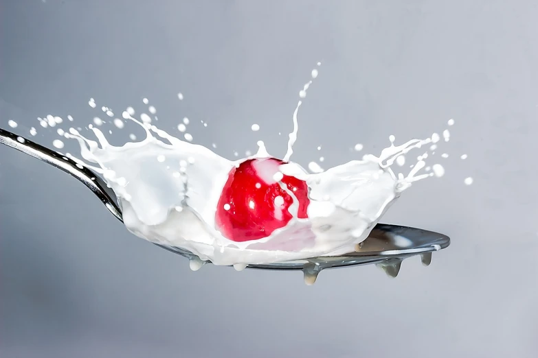 a spoon with milk and a cherry on it, pixabay, digital art, high-speed sports photography, red clown nose, splashing water, on a plate