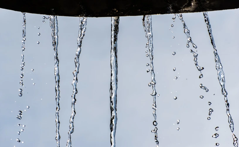 a close up of water dripping from a pipe, inspired by Lucio Fontana, shutterstock, icicles, low angle photo, splash image, spores floating in the air