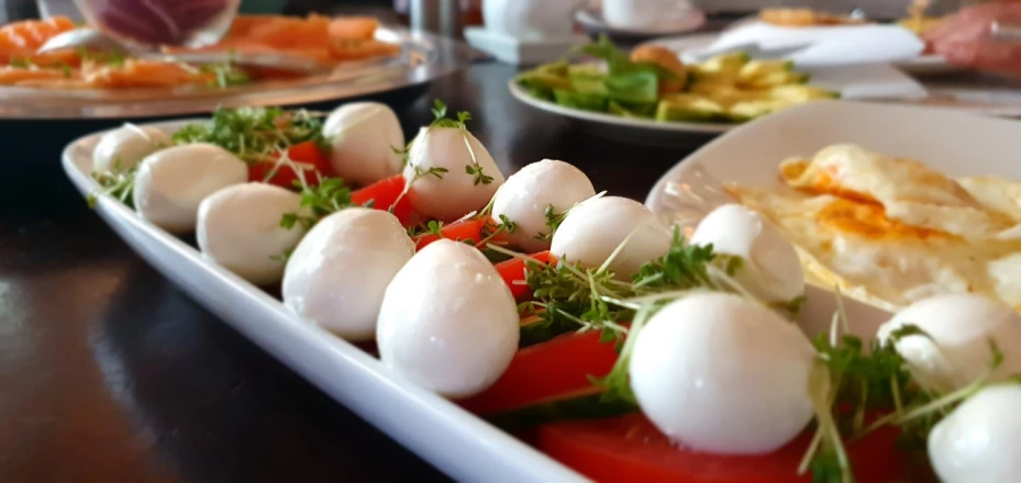 a close up of a plate of food on a table, by Tom Wänerstrand, pexels, lots of mozzarella balls, realistic and coherent, sea of parfait, eggs