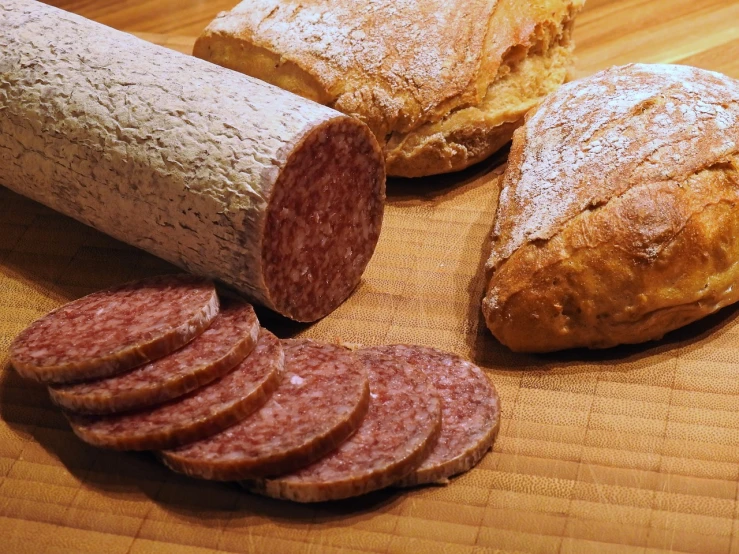 a loaf of bread and slices of sausage on a cutting board, a portrait, by Dietmar Damerau, pexels, meat texture, various posed, coloured, clear detailed view