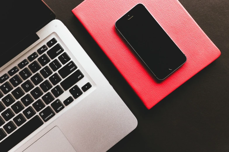 a cell phone sitting on top of a laptop computer, by Romain brook, trending on pexels, hot pink and black, professional iphone photo, red white and black color scheme, using a macbook