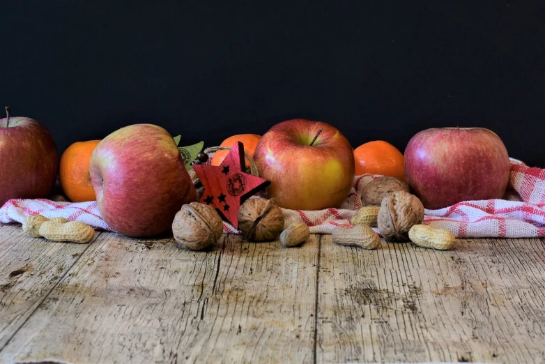 a group of apples sitting on top of a wooden table, a still life, by Helen Stevenson, pexels, festive, 🦩🪐🐞👩🏻🦳, still life photo of a backdrop, nut