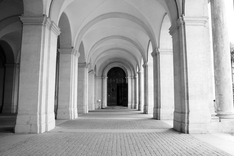 a black and white photo of a hallway, inspired by Pierre Pellegrini, unsplash, high arched ceiling, private academy entrance, pillar, wikimedia commons