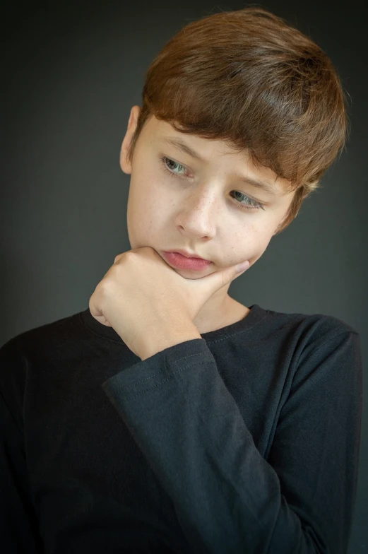 a young boy in a black shirt posing for a picture, a character portrait, by Edward Corbett, shutterstock, realism, hand on her chin, depressed sad expression, stock photo, aged 13