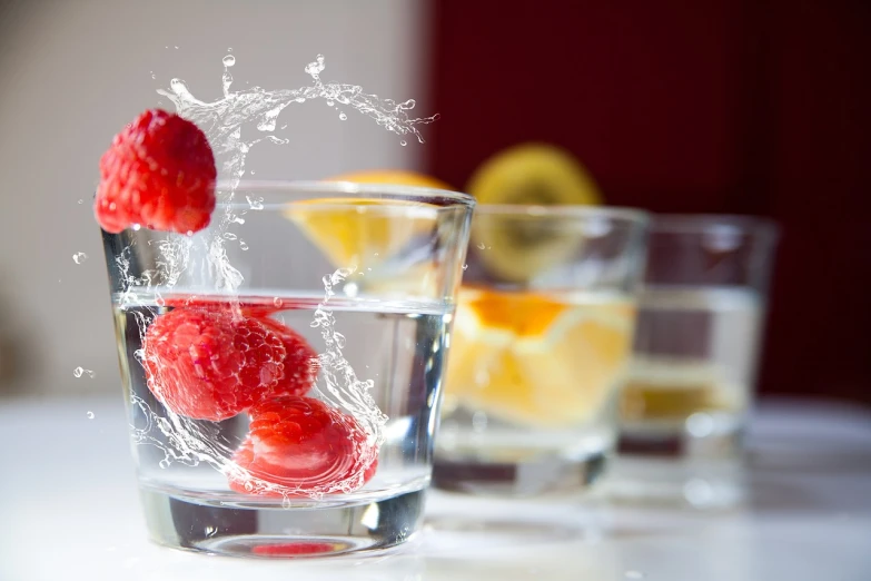 a close up of a glass of water with fruit in it, by Etienne Delessert, pexels, photorealism, food particles, istockphoto, plates of fruit, some red water