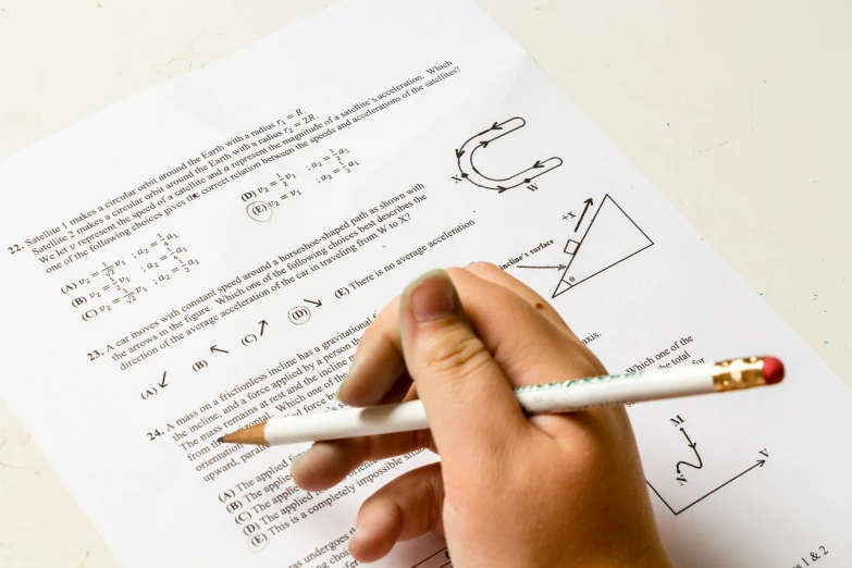a person holding a pencil over a piece of paper, full subject shown in photo, scores, test, 6 4 0