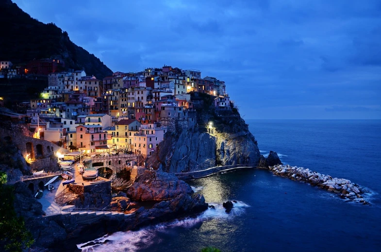 a city on top of a cliff next to the ocean, a picture, by Carlo Martini, beautifully lit buildings, calm vivid colors, quaint, blue