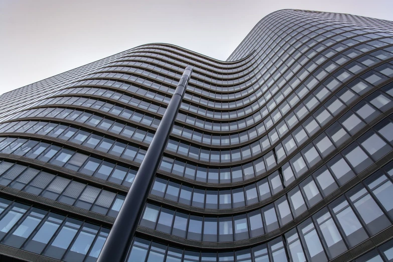 a very tall building with lots of windows, a stock photo, inspired by Zaha Hadid, shutterstock, curving black, ground view, mies van der rohe, real estate photography