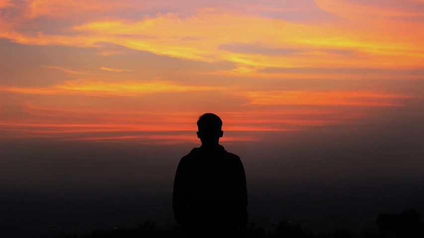 a silhouette of a man standing in front of a sunset, by Jan Rustem, pexels, orange and red sky, contemplation, on top of a hill, photo of a man