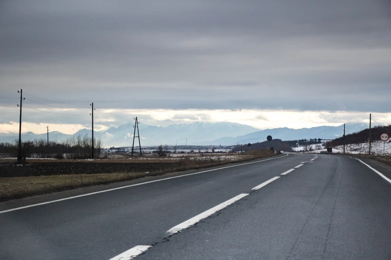 an empty road with mountains in the distance, inspired by Yokoyama Taikan, natural overcast lighting, reportage photo, 7 0 mm photo, ice mountains afar