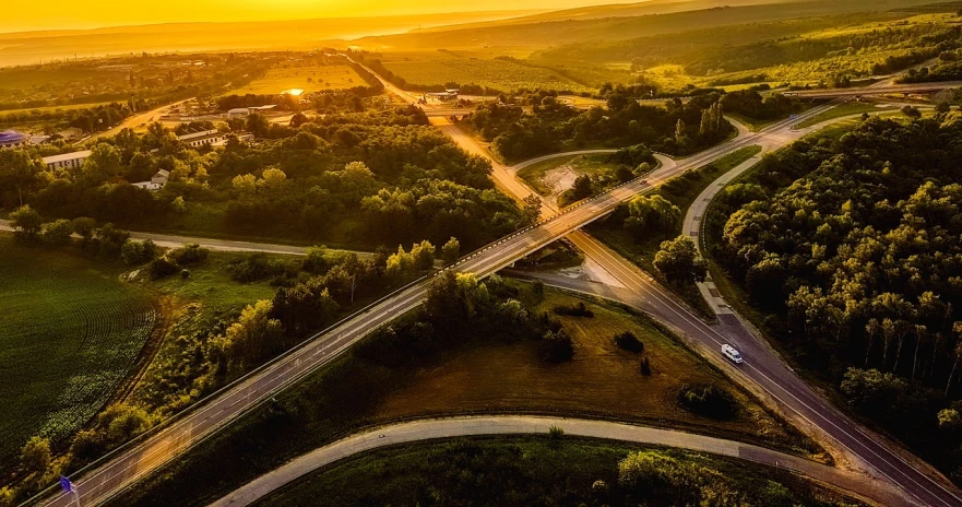 an aerial view of a highway intersection at sunset, a picture, by Thomas Häfner, shutterstock, realism, summer sunset, iowa, at sunrise in springtime, taken with sony a7r camera