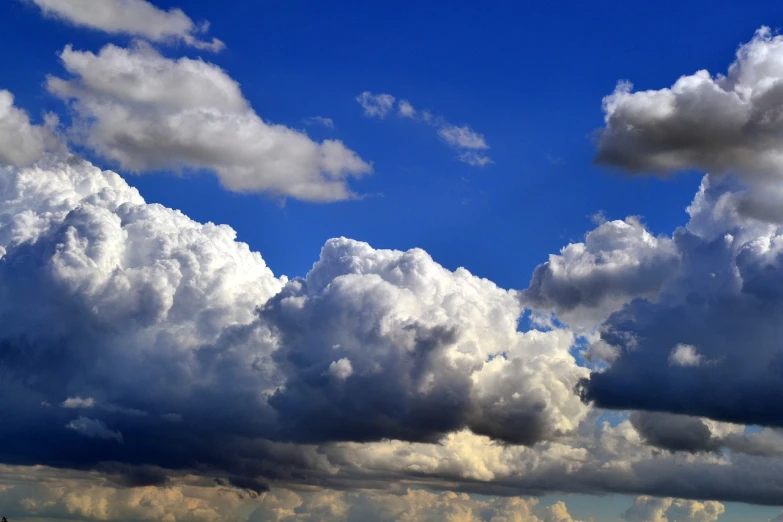 a plane flying through a cloudy blue sky, a picture, by Hans Schwarz, towering cumulonimbus clouds, large clouds, distant rainstorm, there is blue sky