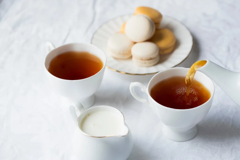 a couple of cups of tea sitting on top of a table, a still life, by Etienne Delessert, pexels, dau-al-set, macaron, white, close-up product photo, marmalade