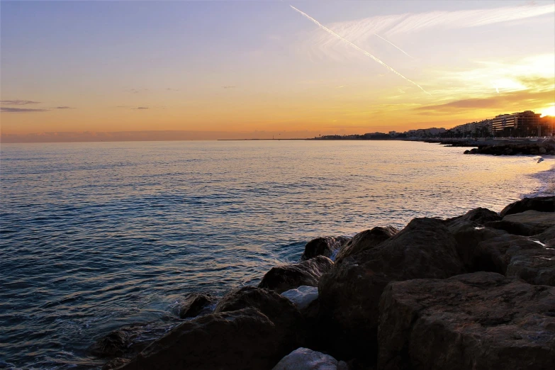 the sun is setting over a body of water, by Alexis Grimou, marbella, shoreline, wide view, from the side