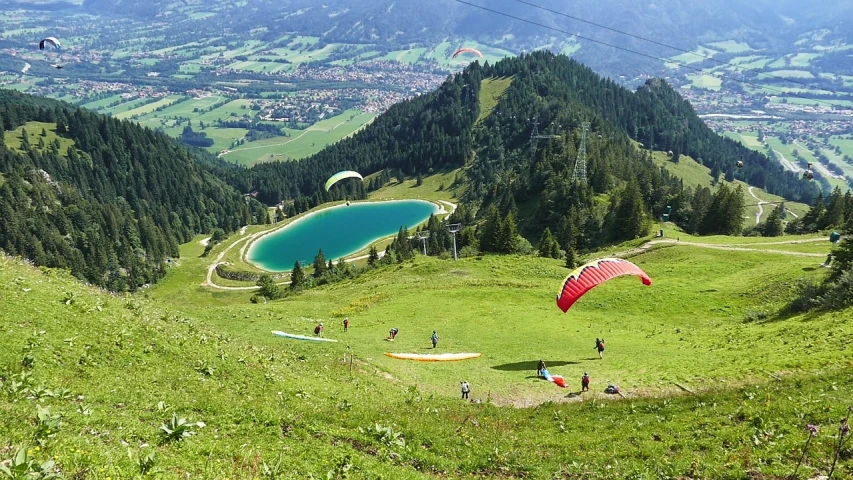 a group of people flying kites over a lush green hillside, by Hans Fischer, flickr, mini lake, by rainer hosch, skydiving, gondolas