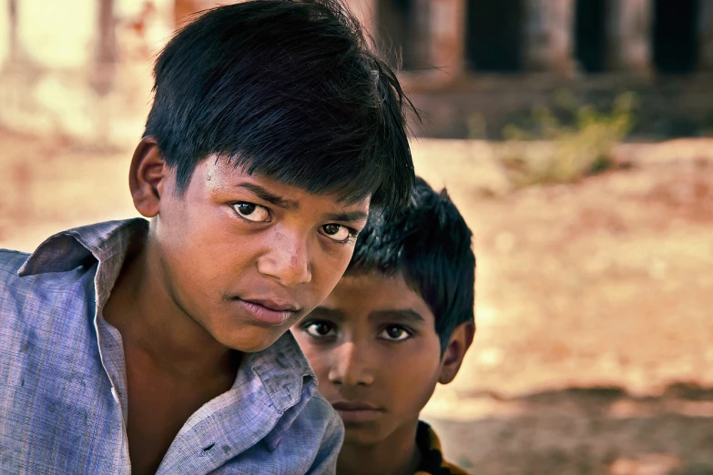 a couple of young boys standing next to each other, a picture, by Rajesh Soni, flickr, piercing glare in the eyes, harsh sunlight, with village, innocent look. rich vivid colors