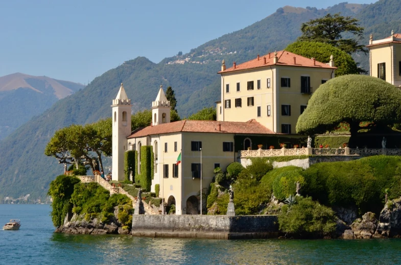 a large building sitting on top of a lush green hillside, inspired by Niccolò dell' Abbate, shutterstock, renaissance, viewed from the harbor, mario testino, lakeside, exquisitely ornate