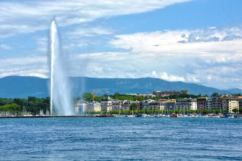 a water fountain in the middle of a body of water, by Alexander Bogen, shutterstock, photo of zurich, srgb, “wide shot, beautiful day