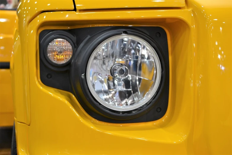 a close up of a headlight on a yellow truck, a portrait, by Jason Felix, renaissance, land rover defender, led light accents, face shown, panel