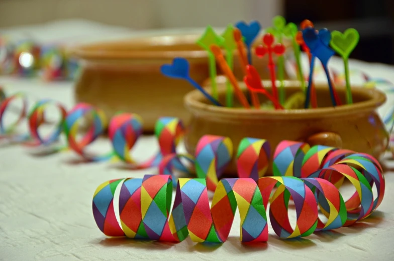 a table topped with lots of colorful paper streamers, a picture, by Hristofor Zhefarovich, shutterstock, wooden art toys, bracelets, ornamental bow, closeup photo