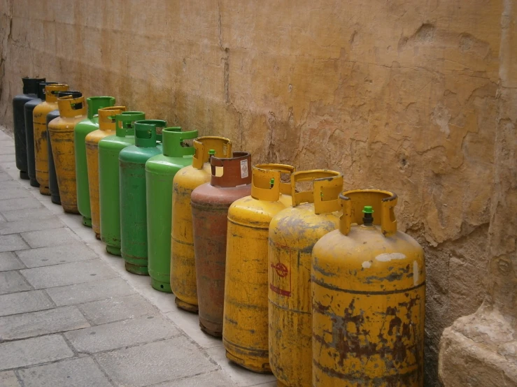 a row of gas bottles lined up against a wall, a photo, renaissance, in egypt, tank, multilayer, colorful”