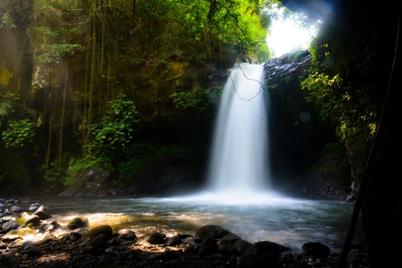 a waterfall flowing through a lush green forest, a picture, by Bernardino Mei, shutterstock, sumatraism, some sun light ray, long exposure photo, big island, backlit!!