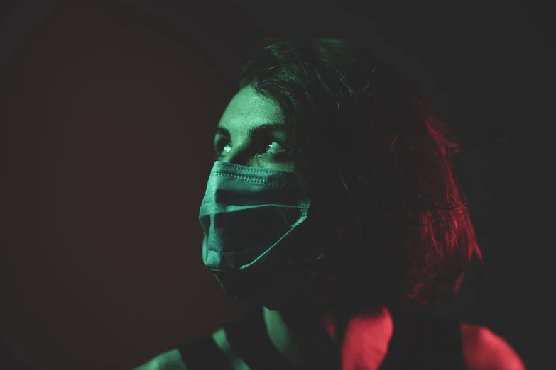 a woman wearing a face mask in the dark, a picture, inspired by Elsa Bleda, portrait of mad lady scientist, full profile, with red haze, healthcare worker