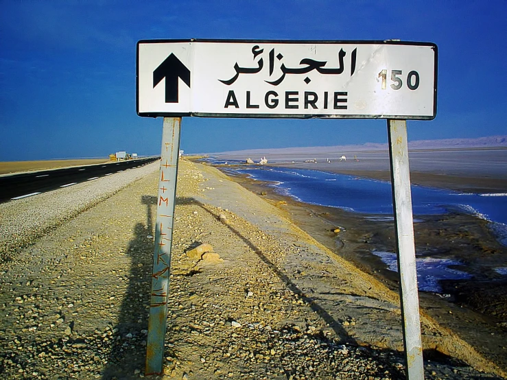 a white street sign sitting on the side of a road, a photo, by Altichiero, arabesque, desert!!!!!!!!!!!, shore, nasreddine dinet, algebra