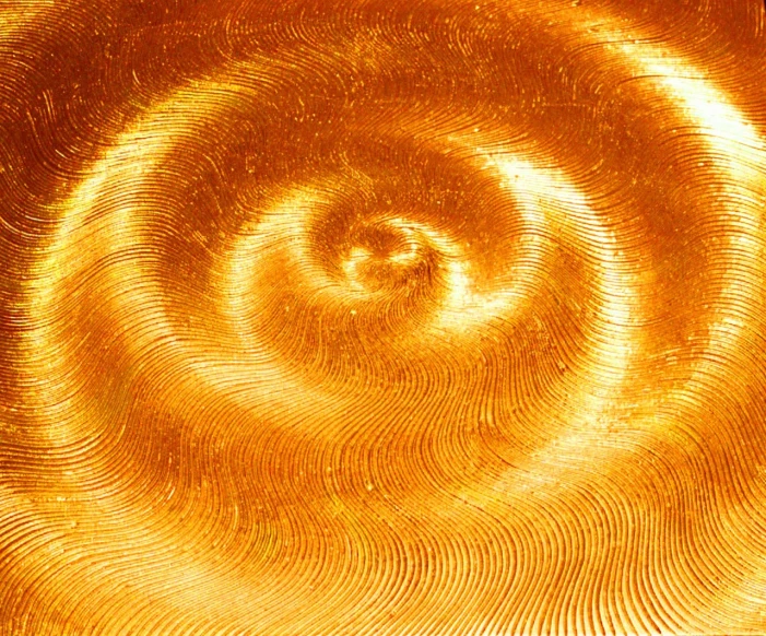 a close up of a spiral design on a surface, flickr, standing in gold foil, amber glow, thailand, grain”