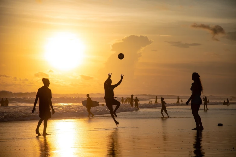 a group of people on a beach playing with a ball, by Matt Stewart, pexels contest winner, bali, action sports, evening sun, horizontally leaping!!!