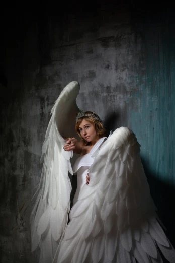 a woman dressed as an angel poses for a picture, a portrait, inspired by Antonio Canova, tattered wings, under studio lighting, wearing a wedding dress, totalitarian socialist angel