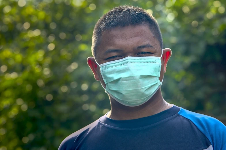 a close up of a person wearing a face mask, a picture, by Jan Rustem, shutterstock, malaysian, young man with short, nepal, green face