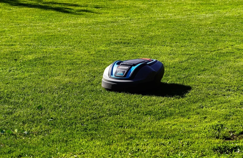 a lawn mower sitting on top of a lush green field, bauhaus, small spot light on robot, blue and red two - tone, with a lush grass lawn, very sharp photo