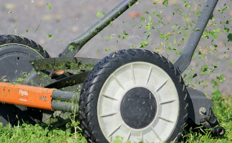 a lawn mower that is sitting in the grass, a picture, by Attila Meszlenyi, pixabay, debris flying around, slow motion, wheel, avatar image