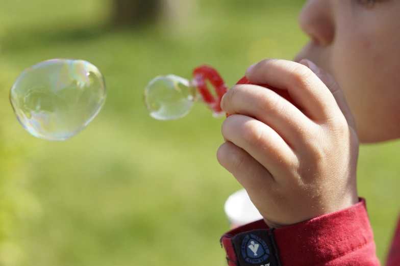 a close up of a child blowing bubbles, a picture, by Jan Rustem, pixabay, inflateble shapes, stock photo