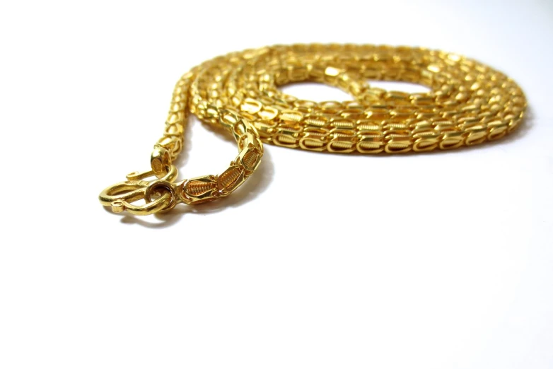 a close up of a gold chain on a white surface, a photo, apophis, high quality product image”, gelbooru, 24k