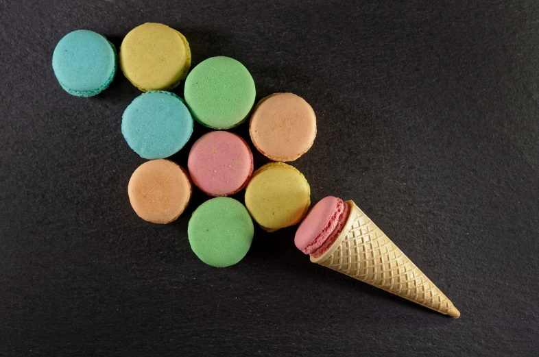an ice cream cone filled with colorful macarons, a pastel, pop art, on black background, photo taken from above, very sharp photo