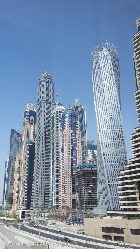 a view of some very tall buildings in a big city, hurufiyya, but not quite, buildings made out of glass, beautiful views, slightly sunny